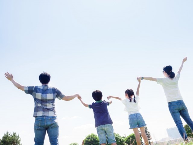 青空に手を上げる家族の写真