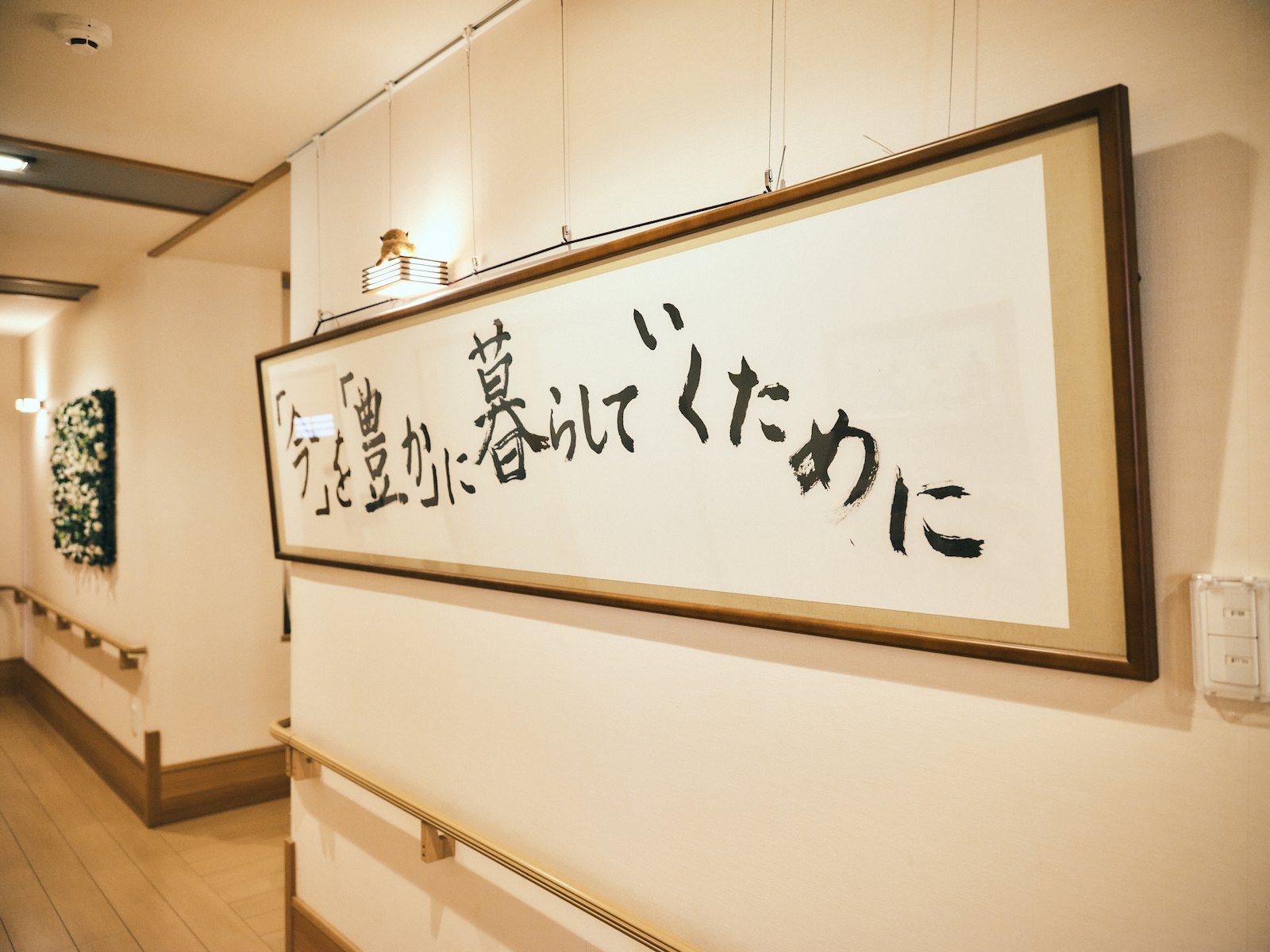 額装され壁に掛けられた標語『「今」を「豊か」に暮らしていくために』