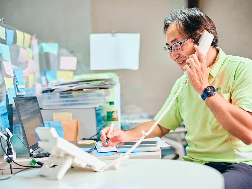 写真：電話中の山根さん