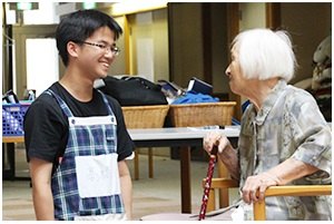 ご利用者様のお年寄りと話をする髙橋さんの写真